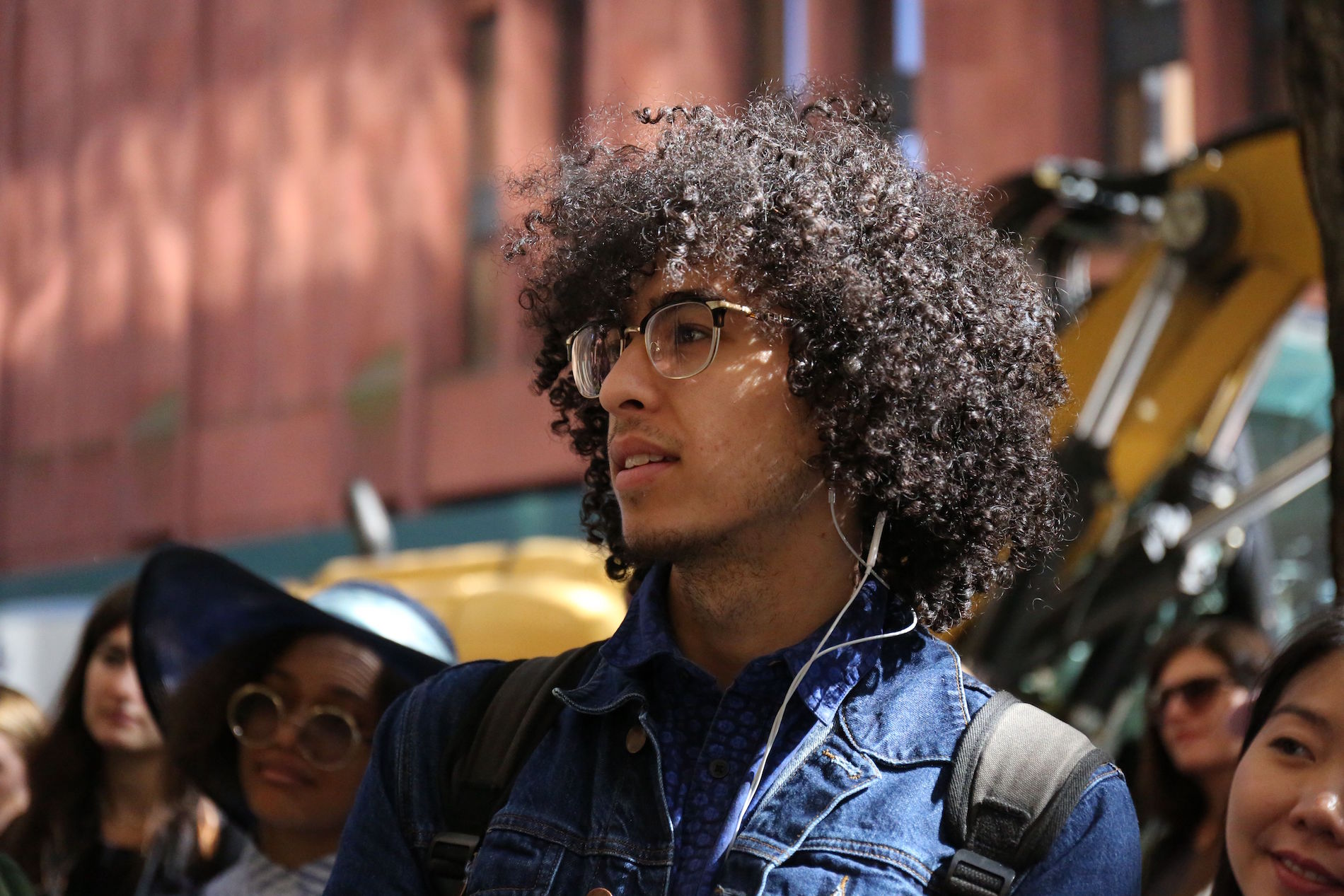 Man with curly brown hair and glasses watches the poetry reading